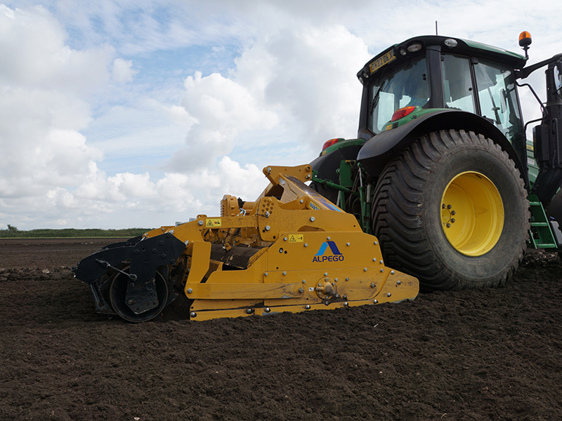 3m Alpego IZ Inversa Stone Burier working behind a John Deere tractor, close-up side angle