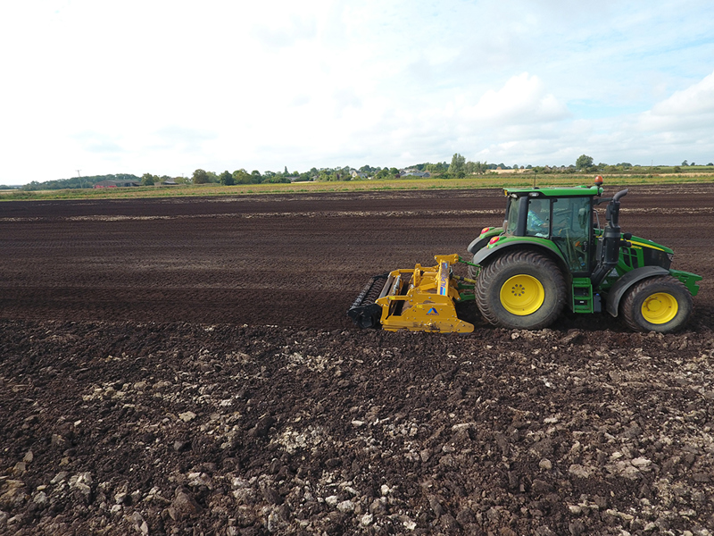 3m Alpego IZ Inversa Stone Burier working behind a John Deere tractor, side angle