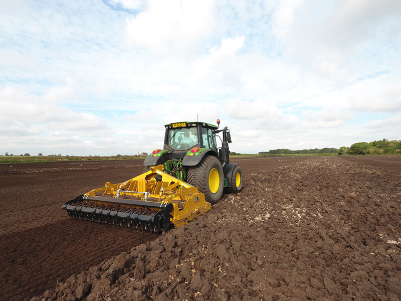 3m Alpego IZ Inversa Stone Burier working behind a John Deere tractor, rear angle