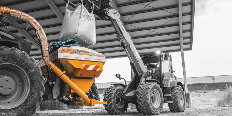 Yellow and black Alpego Front Tank being filled with bag by telehandler, mobile header